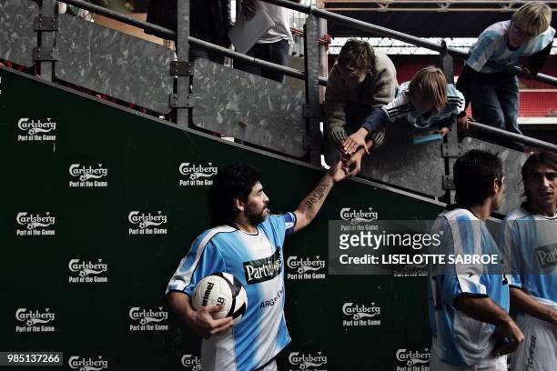 Argentinian soccer legend Diego Maradona shakes hands with fans after a showmatch against a Danish team of retired soccer players lead by Michael...