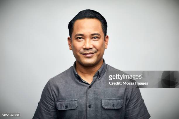portrait of man smiling over white background - asian man studio shot photos et images de collection