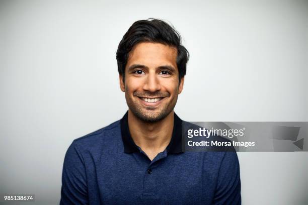 portrait of smiling mid adult man wearing t-shirt - indian faces stock-fotos und bilder