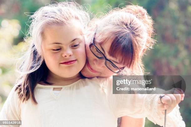 portrait of a mother with her daughter of 12 years old with autism and down syndrome in daily lives - old trying to look young stock pictures, royalty-free photos & images