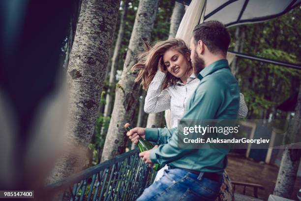 young couple opening champagne bottle for anniversary - drunk husband stock pictures, royalty-free photos & images