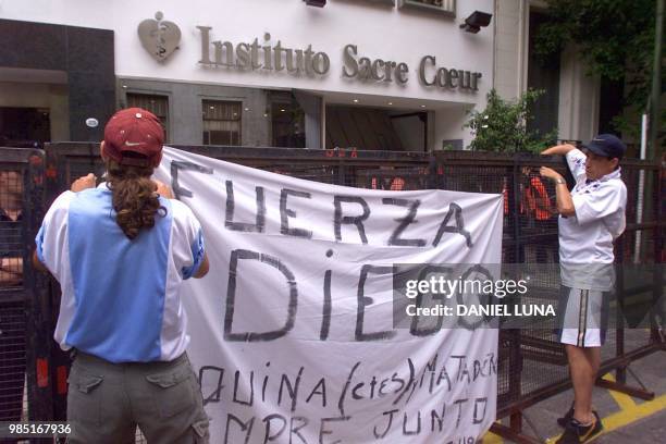 Fans of ex-soccer star Diego Maradona attach a banner 14 January 2000 in Buenos Aires where Maradona is being treated for problems resulting from...