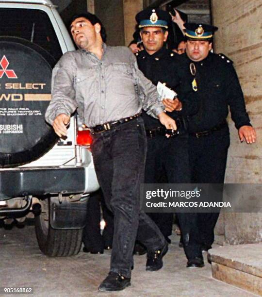 Diego Maradona leaves the courthouse accompanied by police 29 October 1996 after testifying before a judge in Buenos Aires. El futbolista Diego...