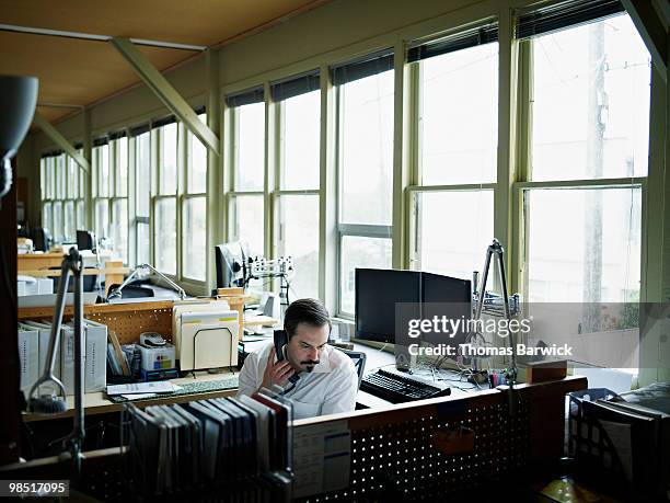 businessman seated at desk on phone - newbusiness stock pictures, royalty-free photos & images