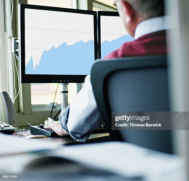 mature businessman examining charts on computer - newbusiness stock pictures, royalty-free photos & images