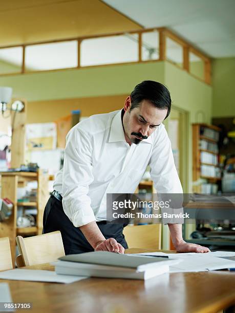 businessman standing looking at paperwork on table - newbusiness bildbanksfoton och bilder