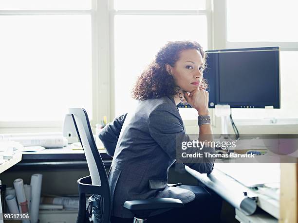 businesswoman seated at desk in office - newbusiness stock pictures, royalty-free photos & images