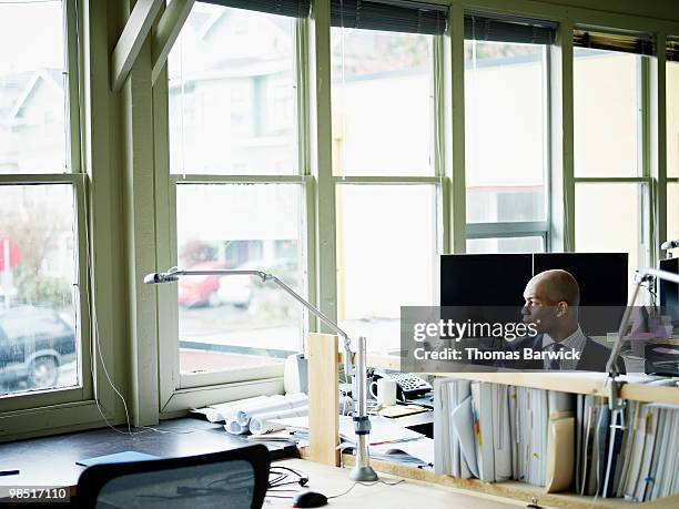 businessman seated at workstation - newbusiness stock pictures, royalty-free photos & images