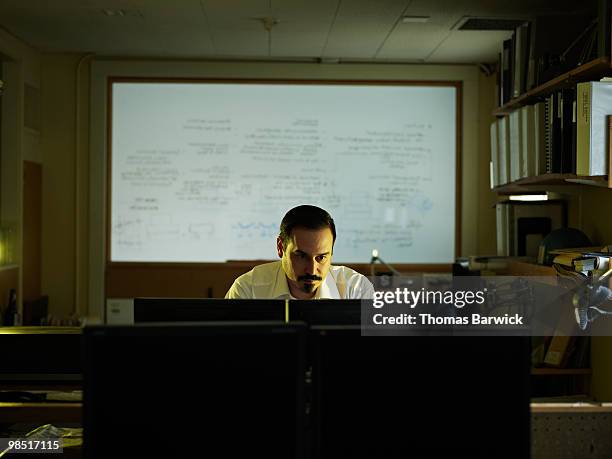 businessman looking at computer monitors in office - newbusiness stock pictures, royalty-free photos & images