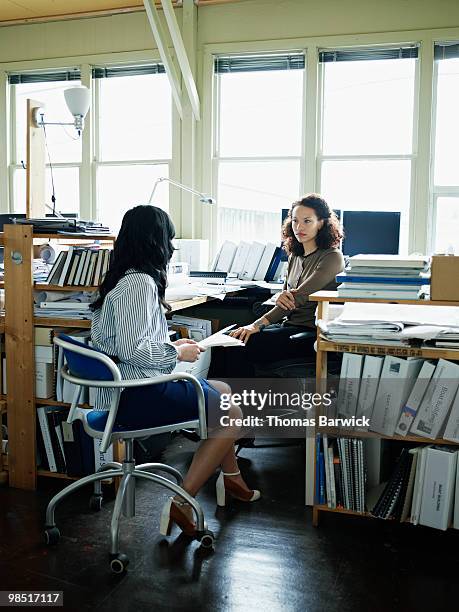 businesswomen in discussion at workstation - newbusiness stock pictures, royalty-free photos & images