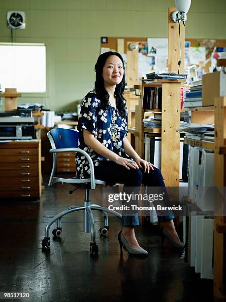 businesswoman seated in office chair smiling - newbusiness fotografías e imágenes de stock