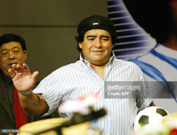 Argentine football idol Diego Maradona holds on to a soccer ball as he arrives for an interview with the Chinese media in Beijing 15 November 2003....
