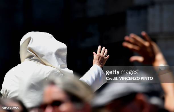 Gust of wind blows Pope Francis's mantle as he waves to people in St. Peters square at the Vatican at the end of his weekly general audience on June...