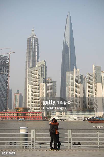 Chinese couple embrace on the promenade of the renovated Bund against Shanghai Jinmao Tower and Shanghai World Financial Center in Lujiazui Financial...