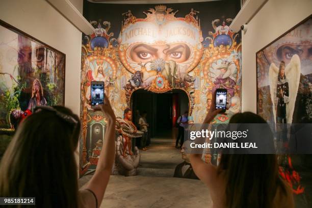 Visitors pose for a picture next to an artwork entitled The King of Pop by US artist Mark Ryden, on display during a photocall to promote the...