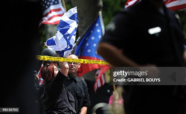 Member of the neo-nazi group, The American National Socialist Movement, tears an Israeli flag during a rally in front of the Los Angeles City Hall,...