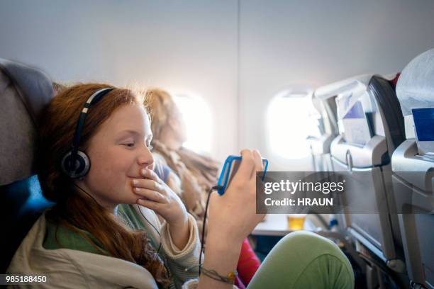 niña en un avión viendo una película en un teléfono móvil - aircraft wifi fotografías e imágenes de stock