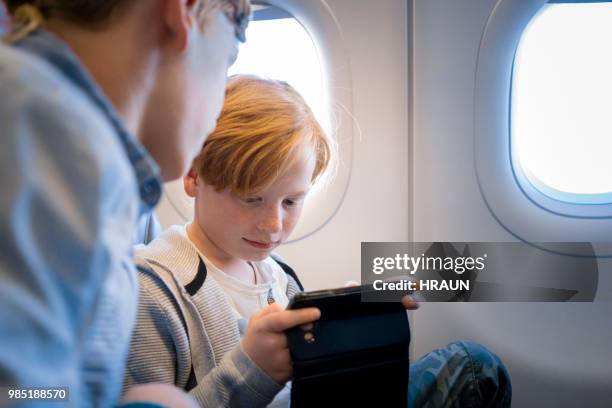 junge mit smartphone in einem flugzeug unterwegs - bruder stock-fotos und bilder