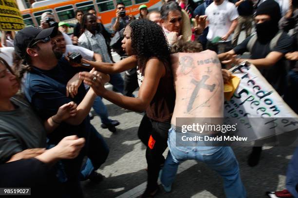 Woman tries to stop an attack on a reportedly homeless man by anti-neo-Nazi demonstrators near people holding a Freedom of Speech placard before the...