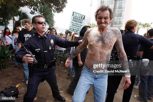 Police officer assists a reportedly homeless man who was attacked by anti-neo-Nazi demonstrators before the start of a rally by the National...