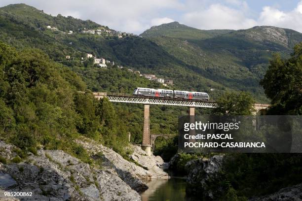 Train travels on a railway bridge above the Golo river, with the villages of Prunelli di Casacconi and Olmo in the background, near Barchetta, on...