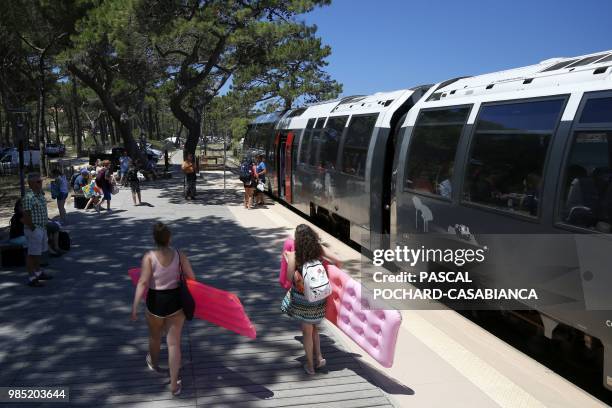 Tourists walk next to a train heading to the beach from the Calvi train station on June 26, 2018 on the French Mediterranean island of Corsica. -...