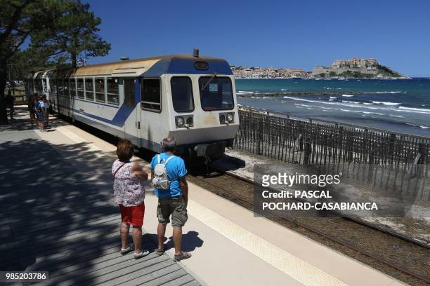Tourists wait for the train heading to the beach from the Calvi train station on June 26, 2018 on the French Mediterranean island of Corsica. - Since...