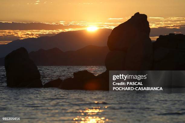 The sun is pictured above the Cap-Corse peninsula during sunrise in L'Ile-Rousse on the French Mediterranean island of Corsica, on June 26, 2018.