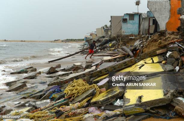 An Indian resident collects usable form his damaged house at a fishing hamlet of Srinivasapuram on the coast of Bay of Bengal in Chennai on June 27,...