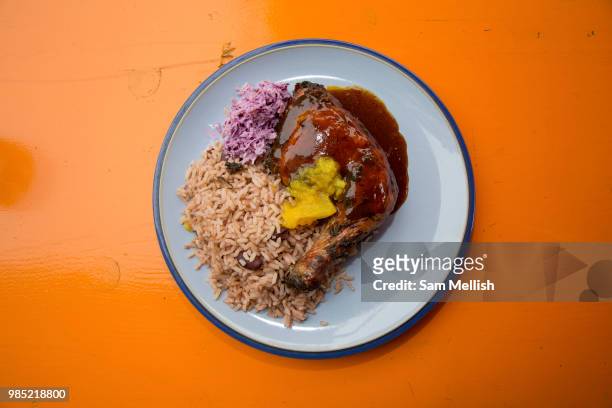 Jerk chicken with rice and peas on an orange table at Fish Wings & Tings, a Caribbean restaurant in Brixton Village on the 23rd June 2018 in Brixton...