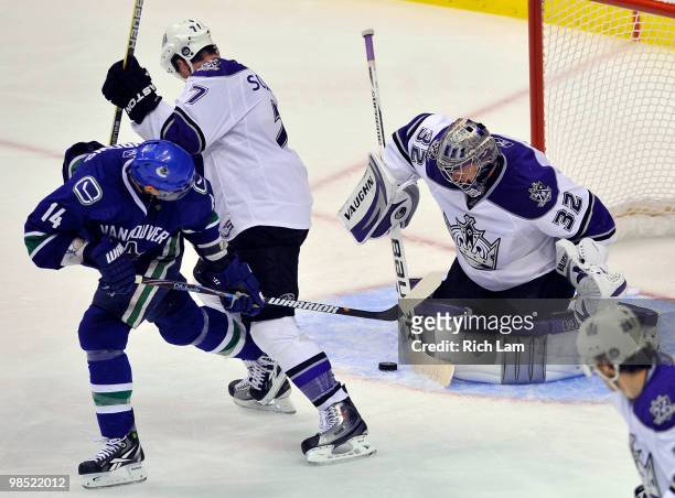 Alex Burrows of the Vancouver Canucks gets a shot on goalie Jonathan Quick of the Los Angeles Kings while being ties up by Rob Scuderi during the...