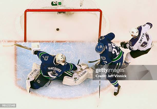 Ryan Smyth of the Los Angeles Kings and Alexander Edler of the Vancouver Canucks look on as the shot of Wayne Simmonds of the Los Angeles Kings gets...