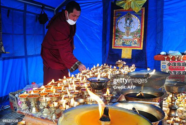Tibetan Buddhist monk lights butter lamps for the dead at a makeshit tent in Jiegu, Yushu County, on April 18, 2010 following the April 14 6.9...