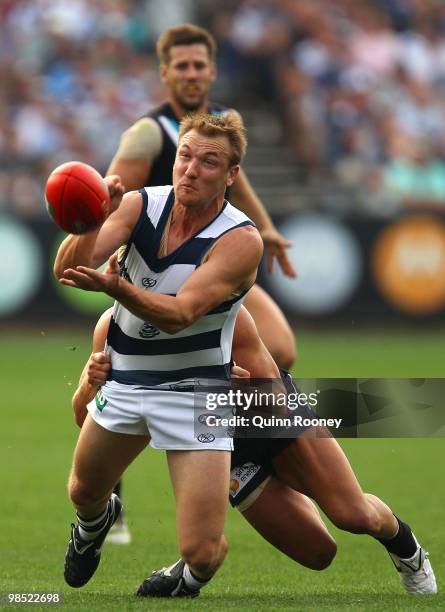 Darren Milburn of the Cats handballs whilst being tackled during the round four AFL match between the Geelong Cats and the Port Adelaide Power at...