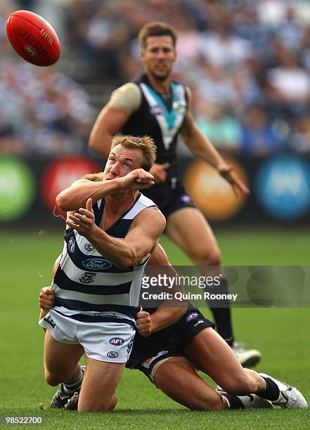Darren Milburn of the Cats handballs whilst being tackled during the round four AFL match between the Geelong Cats and the Port Adelaide Power at...