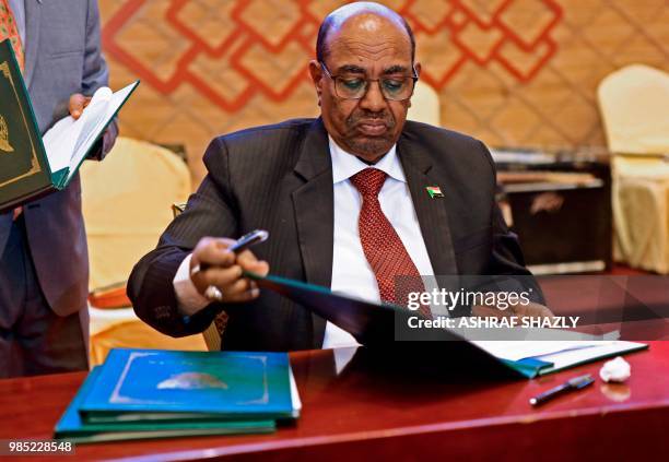 Sudanese President Omar al-Bashir looks at documents that he signed after the two South Sudanese arch-foes agreed in Khartoum on June 27 to a...