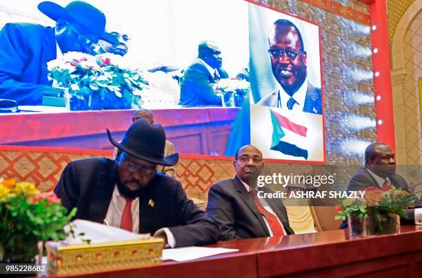 Salva Kiir prisedent of south Sudan signs documents as Sudanese President Omar al-Bashir and South Sudanese rebel leader Riek Machar are seated after...