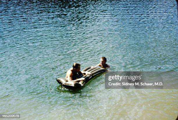View, from above, of Chuck Hatfield and Captain Jim C Jones, of the 8063rd MASH , as they swim with an inflatable raft, South Korea, August 1952.