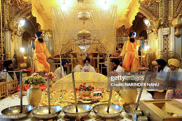 Indian Sikh priest Mal Singh sits behind the Guru Granth Sahib as 'Jalau', a splendour show of Sikhism's symbolic items, is displayed inside The...