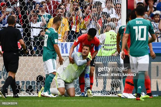 Germany's goalkeeper Manuel Neuer reacts as South Korea's forward Son Heung-min helps him to stand up during the Russia 2018 World Cup Group F...