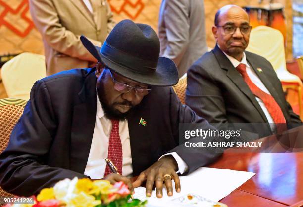 Salva Kiir prisedent of south Sudan signs documents as Sudanese President Omar al-Bashir is seated after the two South Sudanese arch-foes agreed in...