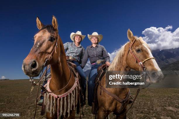 två cowgirls på hästryggen lutar nära - strobe light bildbanksfoton och bilder