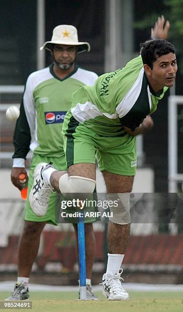 Pakistan cricket coach Waqar Younis and captain Shahid Afridi watch teammate Abdul Razzaq deliver a ball during the final day of a practice camp at...