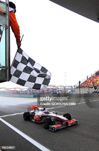 McLaren-Mercedes driver Jenson Button of Britain drives pass the chequered flag to win Formula One's Chinese Grand Prix in Shanghai on April 18,...