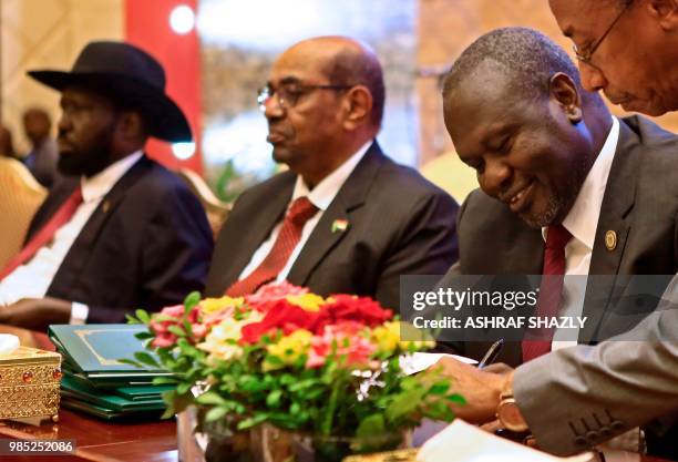 South Sudanese rebel leader Riek Machar signs documents as Sudanese President Omar al-Bashir and South Sudan President Salva Kiir are seen seated...