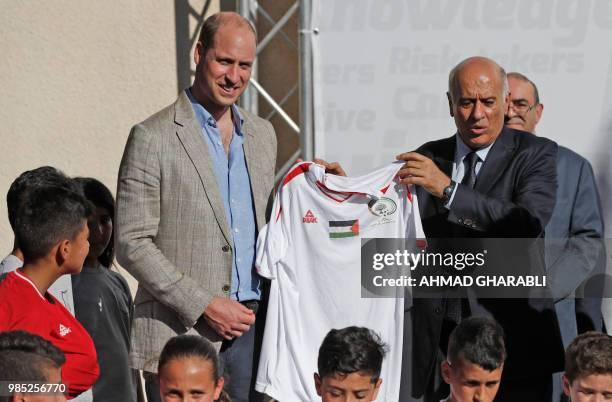 Head of the Palestinian Football Federation, Jibril Rajoub , offers a football jersey to Britain's Prince William in the West Bank city of Ramallah...