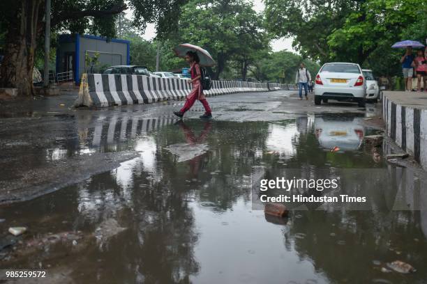 School girl holds umbrella as she walks through a water logged road after the Capital witnessed a spell of pre-monsoon showers near Sheikh Sarai, on...