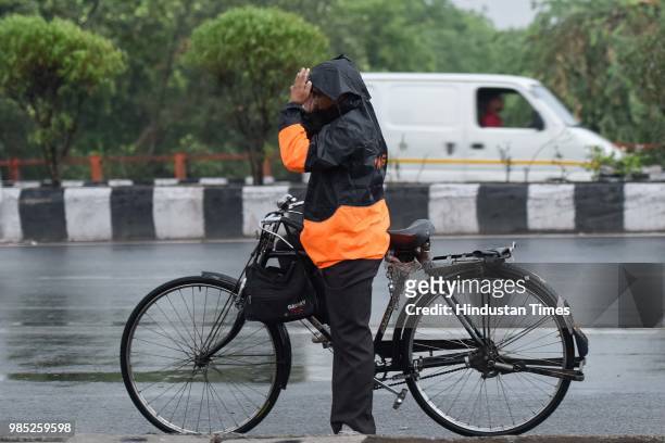 Man covers himself with a rain jacket during the pre-monsoon showers near Sheikh Sarai, on June 27, 2018 in New Delhi, India. The monsoon rains are...
