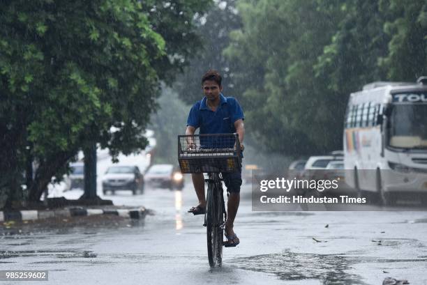 Man rides a bicycle during the pre-monsoon showers near Sheikh Sarai, on June 27, 2018 in New Delhi, India. The monsoon rains are expected to arrive...