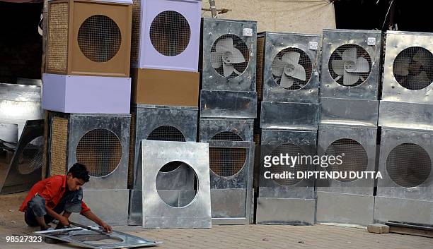 Young Indian worker makes coolers in Allahabad on April 18, 2010. The coolers use a fan to filter air through wet straw and are used as a low-energy...